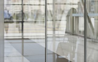 spiegelung-einer-frau-die-auf-eine-automatiktuer-zugeht
