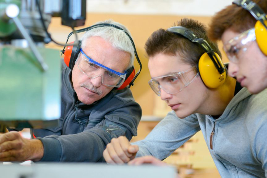zwei-auszubildende-werden-von-einem-mitarbeiter-bei-der-glasverarbeitung-eingewiesen